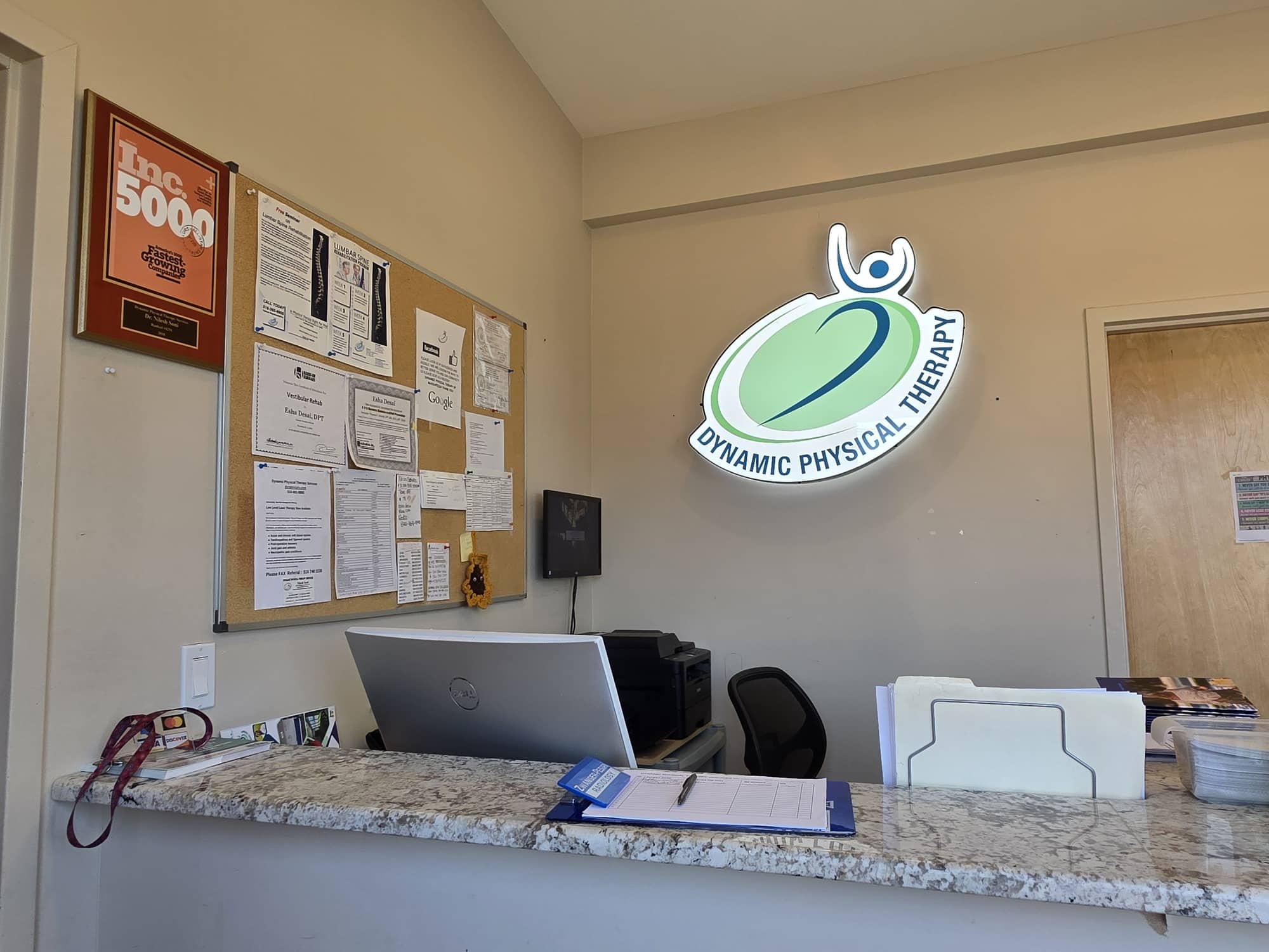 Reception desk at Dynamic Physical Therapy Massapequa with branded sign and Inc 5000 award